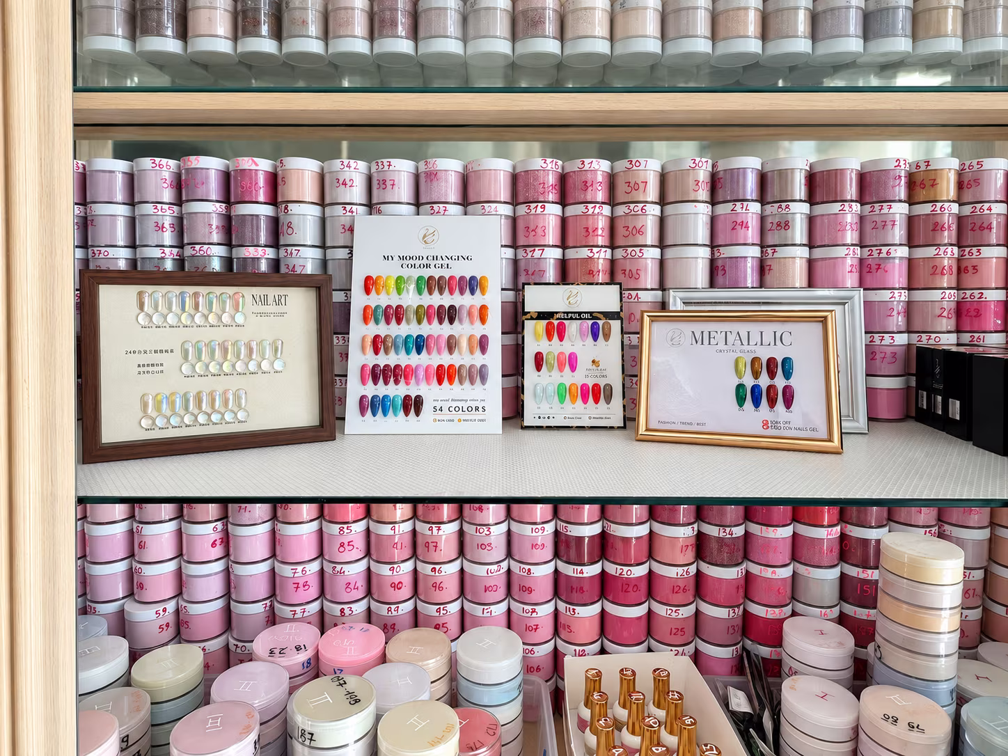 Wall of dip powder and gel color jars with swatch boards at Allure Nails